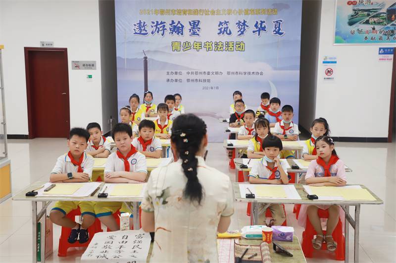 2021年7月10日，鄂州市科协组织莲花小学学生在鄂州市科技馆开展社会主义核心价值观系列活动，图为开展的遨游翰墨筑梦华夏书法活动，老师讲解握笔姿势2.jpg
